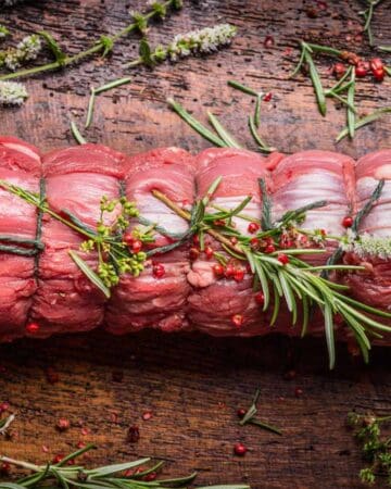 baron of beef roast raw beef with herbs on the wooden board