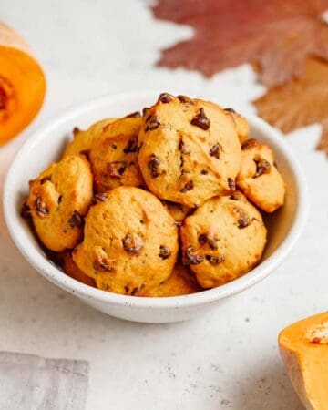 Gluten free pumpkin chocolate chip cookies in the bowl along with pumpkin and leaves on the side.