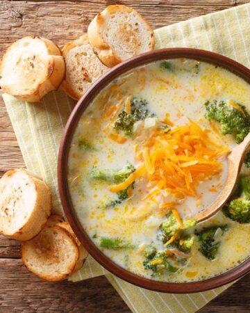 spicy broccoli cheddar soup in a bowl with the spoon,bread along with towel